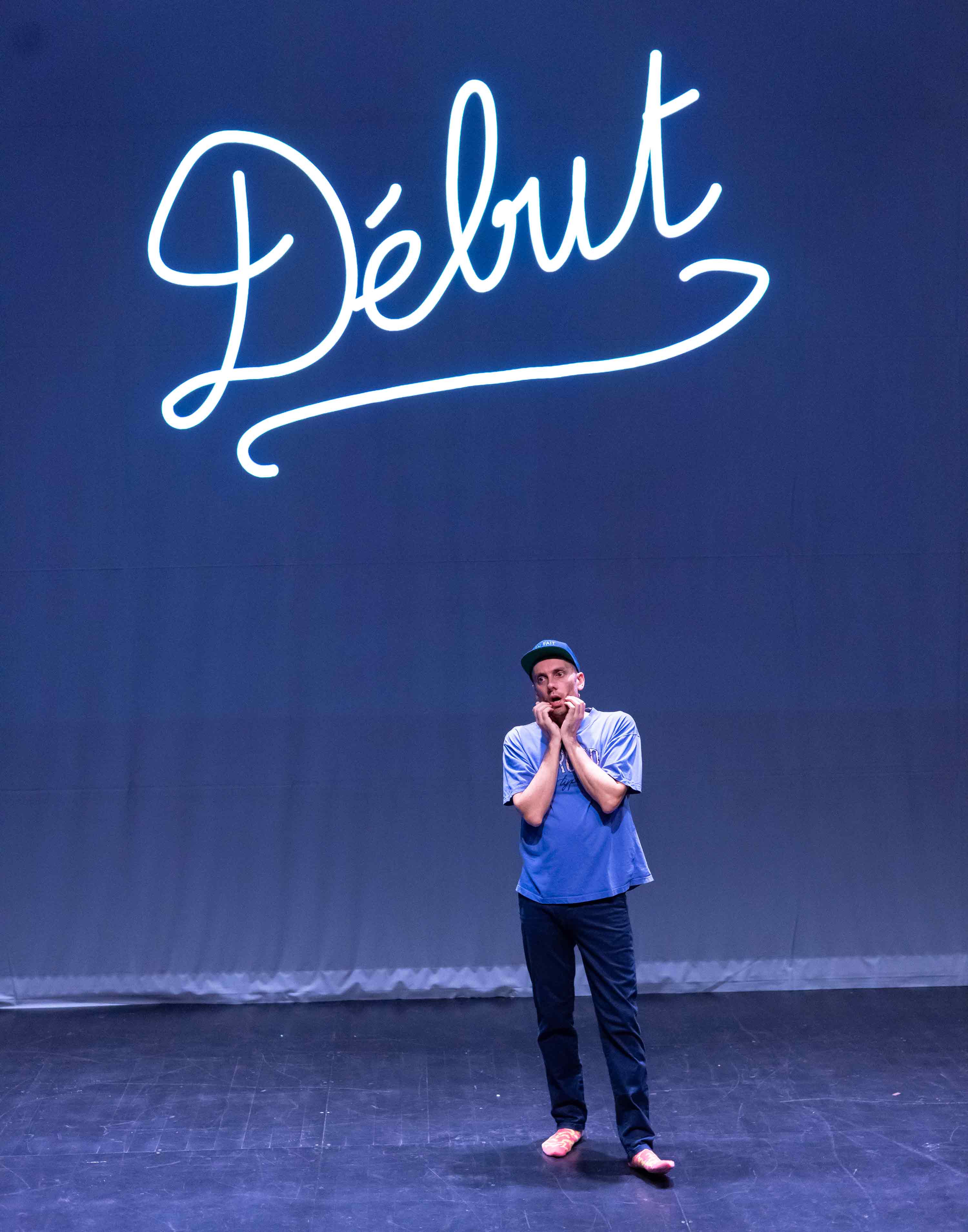 Antoine Defoort arbore un air particulièrement soucieux. Derrière lui, sur un écran de projection, on peut lire le mot 'Début'